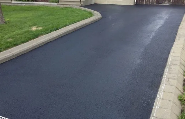 Freshly laid tarmacadam driveway with clean block paving edging and green lawn border - completed by Casey Paving Ltd