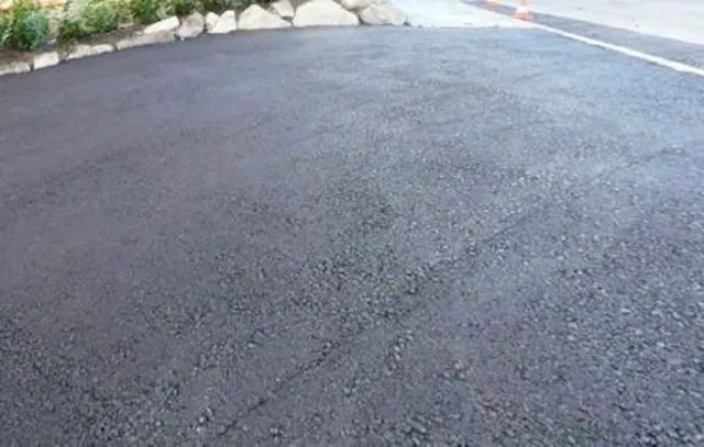 Fresh tarmacadam surface showing texture alongside stone border
